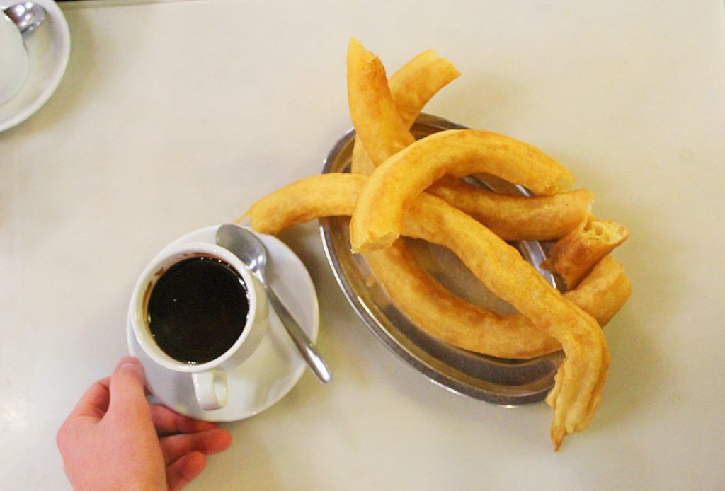 Churros on the side of a cup of chocolate.